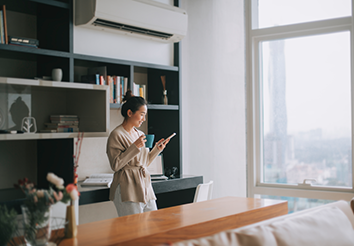 woman standing holding cup looking at phone